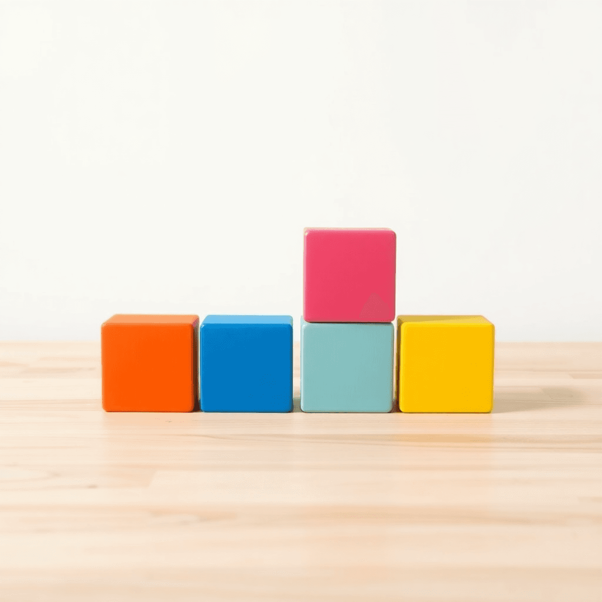 Four colorful building blocks arranged neatly on a light wooden surface with soft natural lighting and a minimalistic background.